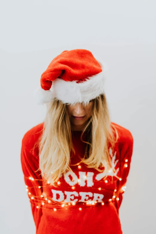 woman with santa hat looking down in front of a white background