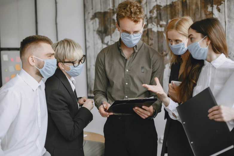 three people wearing masks standing near each other in a room