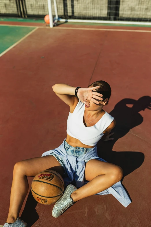 a woman sits on the court and holds her face near her eyes