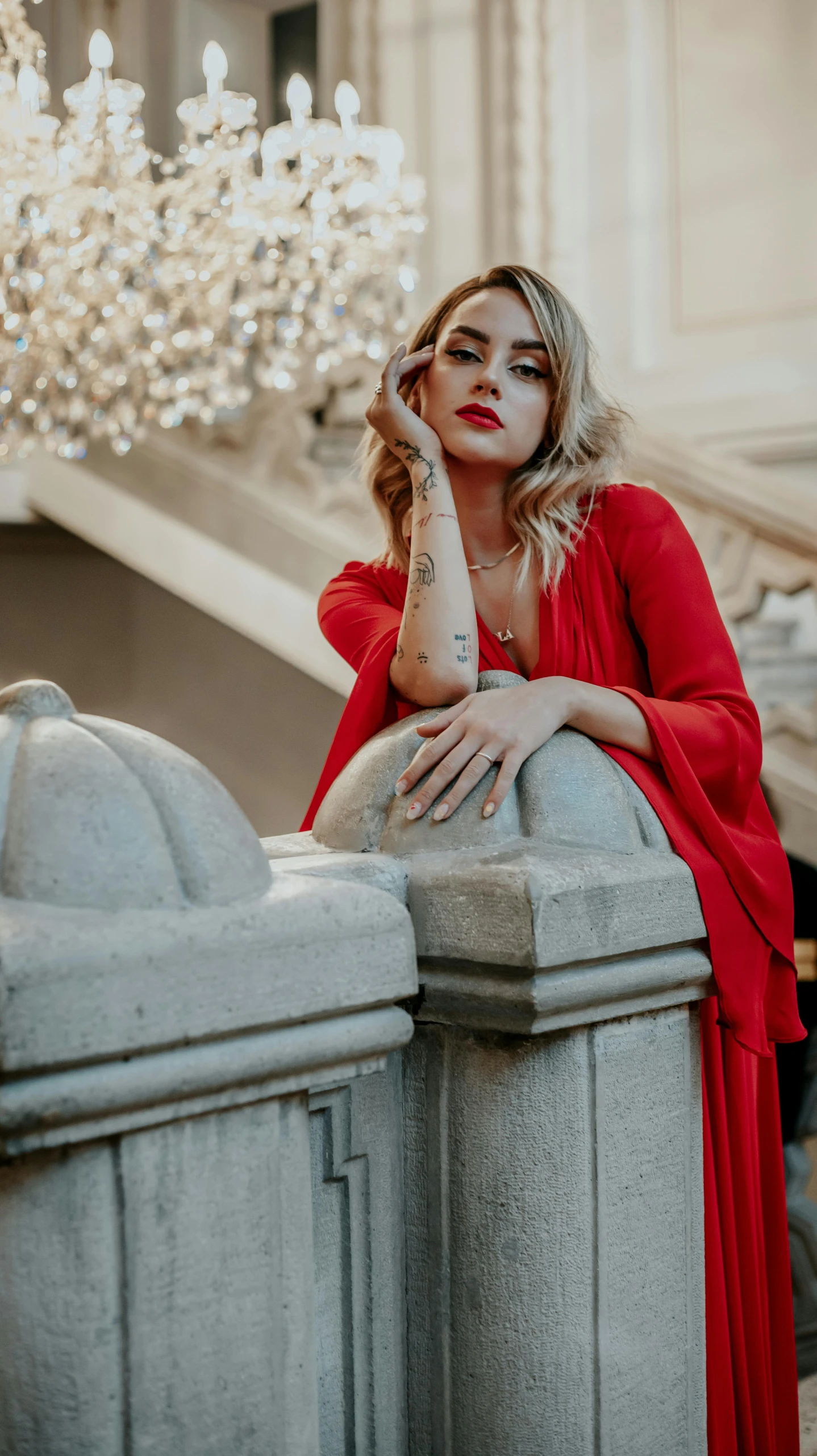 a beautiful blonde woman leaning on the side of a building