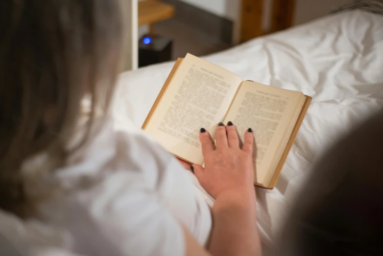 a woman is reading a book in bed