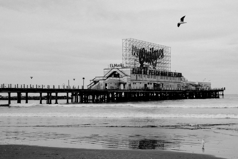 a pier with a bird flying over it near the water