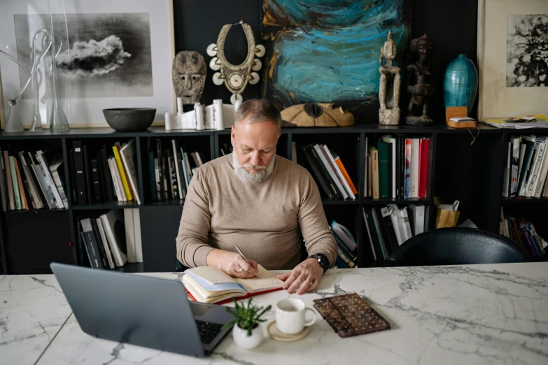 man in the kitchen writing on a book