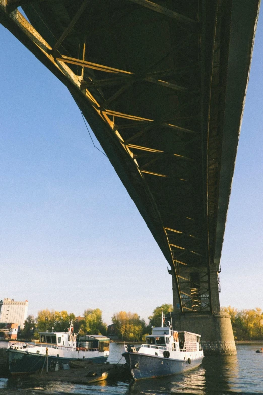 there are boats parked on the water under a bridge