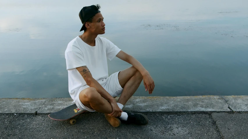 a man sitting on top of concrete near water