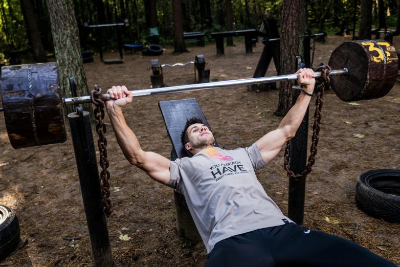 a man is doing an overhead - squat exercise on a bench in the forest