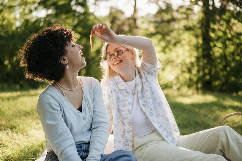 the women laugh as they sit on the grass