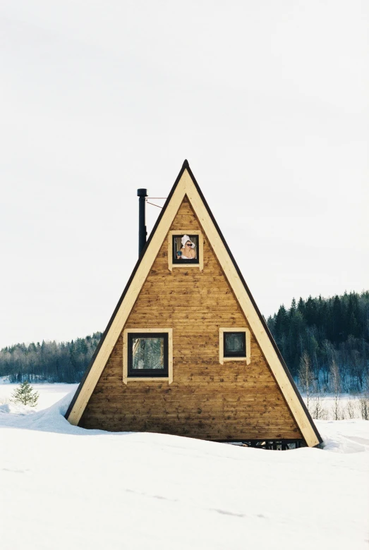 a triangular building with two windows in snow