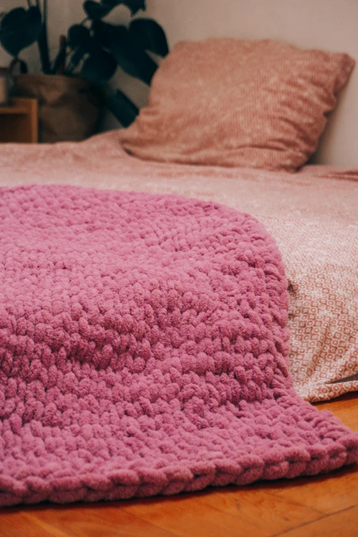 an oversized pink blanket rests on a wooden floor