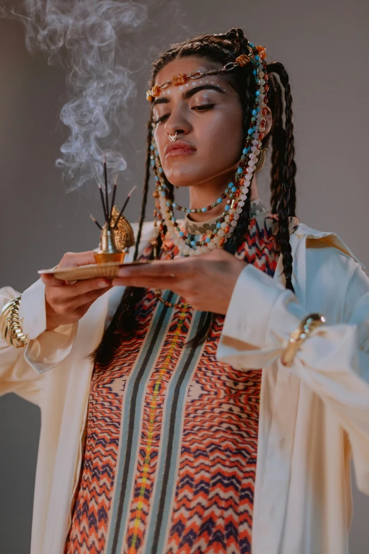 an old woman wearing ethnic garb holds up incense sticks