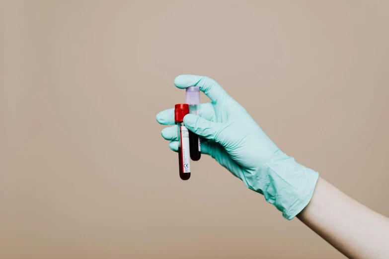 the gloved hand is holding the small red and white toothbrush