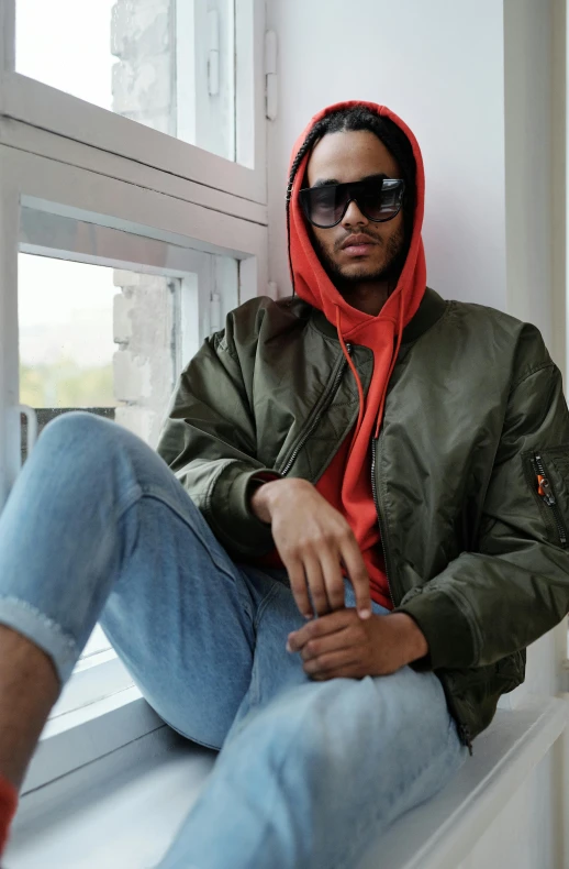 man in jacket sitting on window ledge with eyeglasses