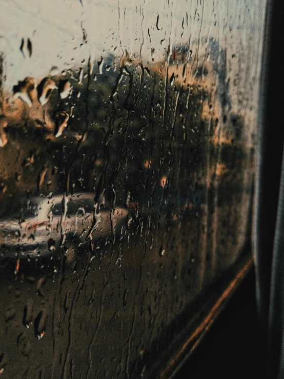 some rain is falling down on the window of a train