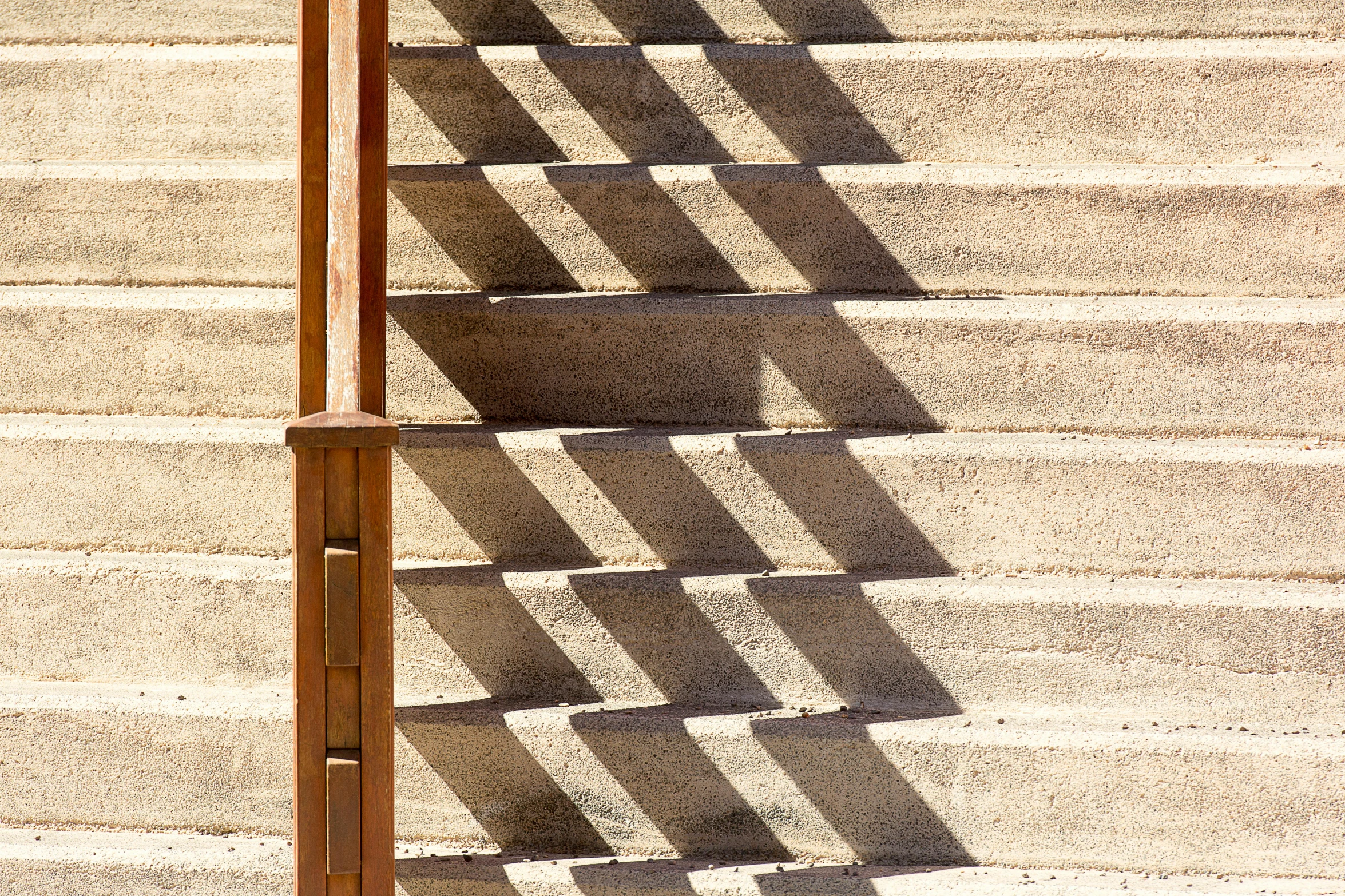 a railing has shadows on it as it stands against the concrete