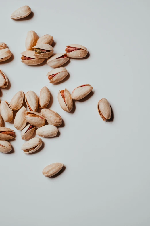 pistachio - colored nuts scattered on white surface