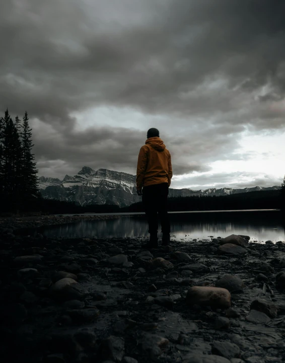 man standing by the water looking out to a mountain range