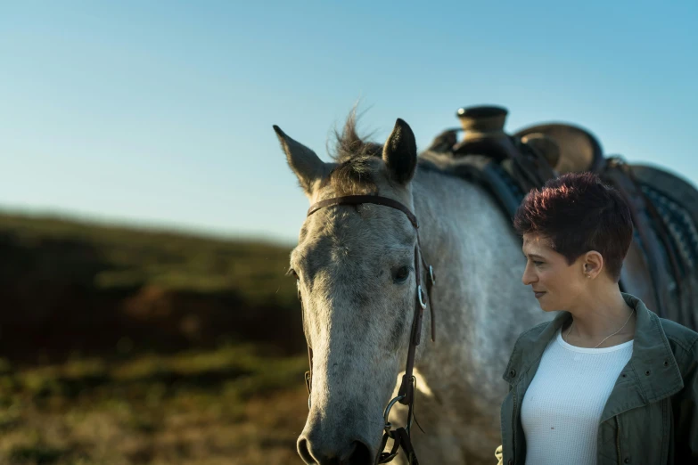 a woman is standing with a horse in the middle of the country