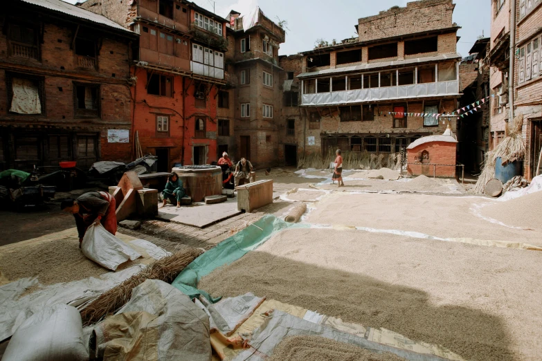 a person sitting in a courtyard, looking at a person with a basket