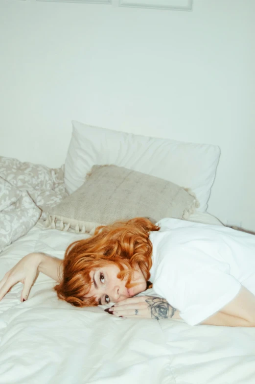 a woman laying on top of a bed wearing a white shirt