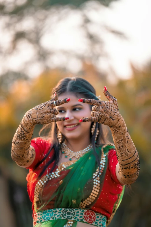 a woman with red and green jewelry wearing a red sari