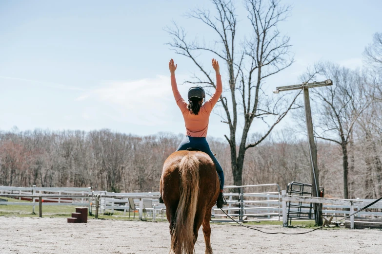 a young lady stands on a horse that is raised her hands