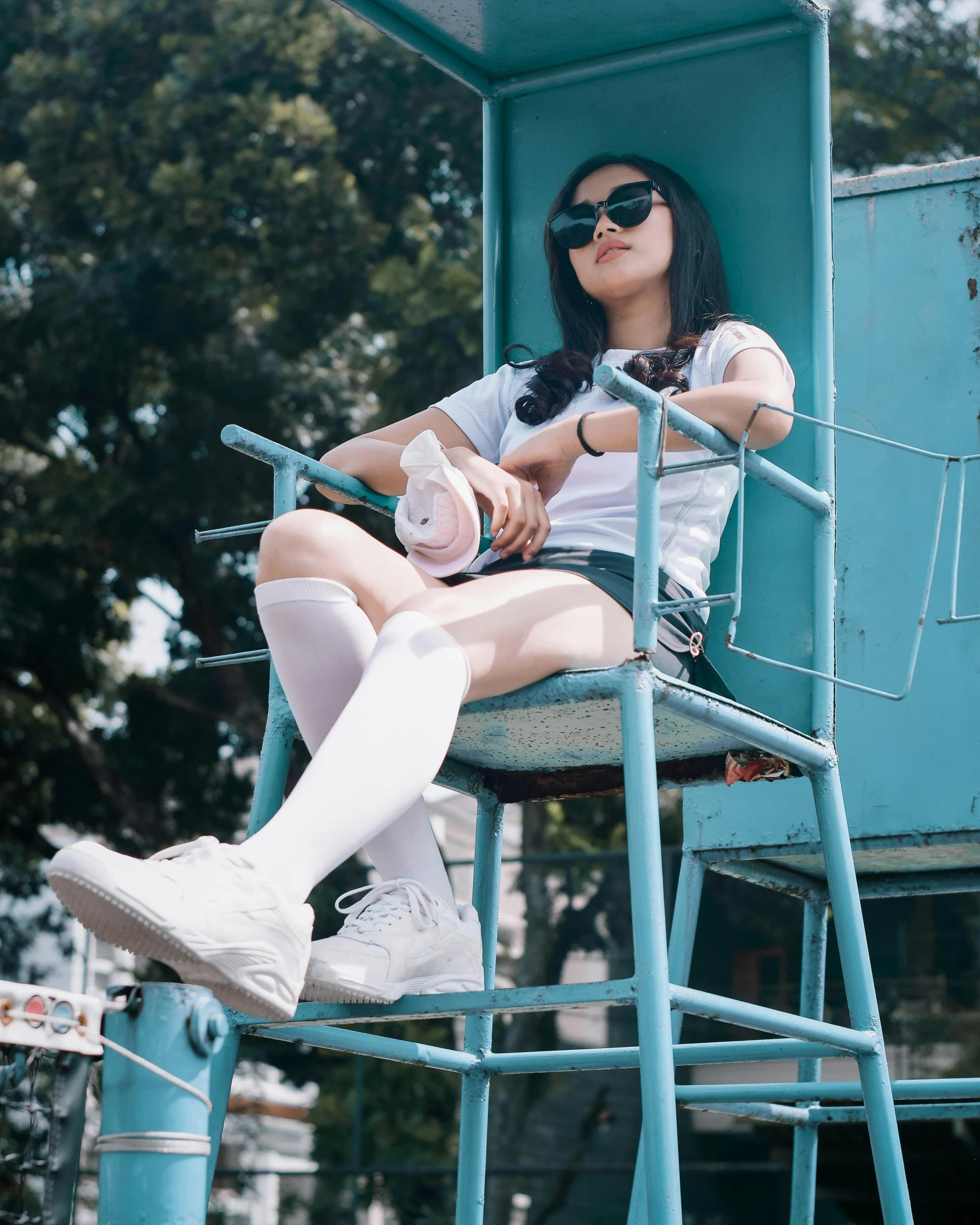 a woman sitting on a tall blue bench holding a bottle