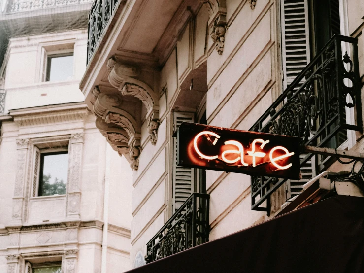 a cafe sign hanging from the side of a building