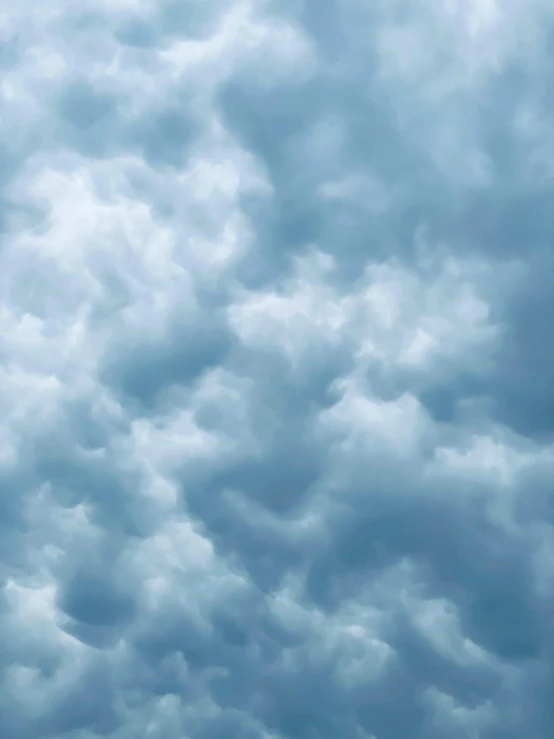 a plane flying under a cloud covered sky