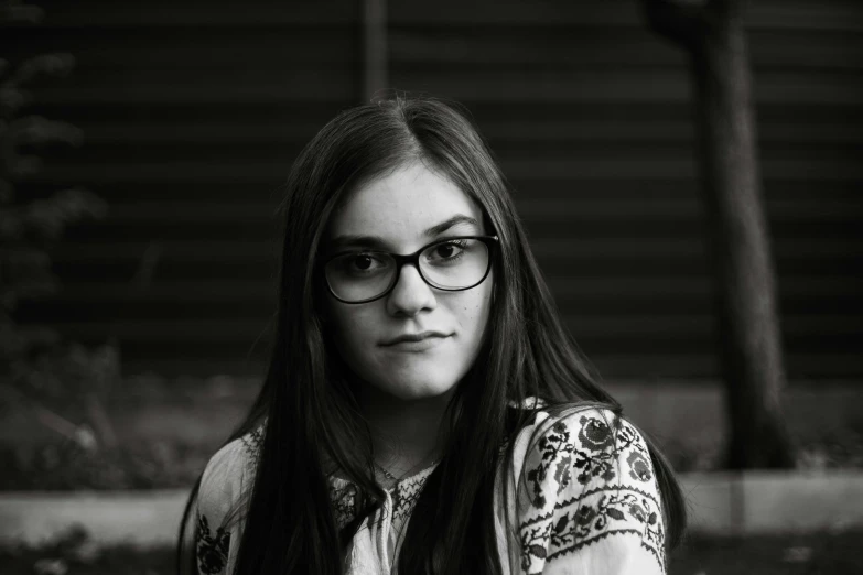 a girl wearing glasses is staring at the camera