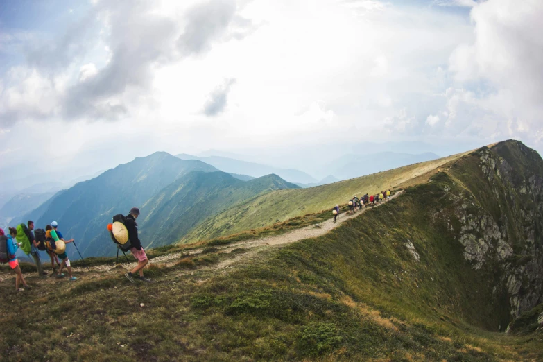 several hikers climb a steep grassy and hilly area