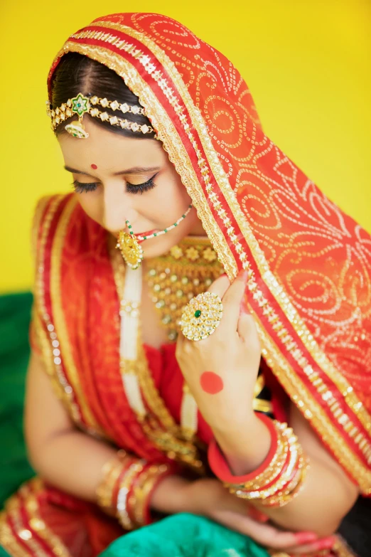 a woman in red and gold is wearing traditional sari