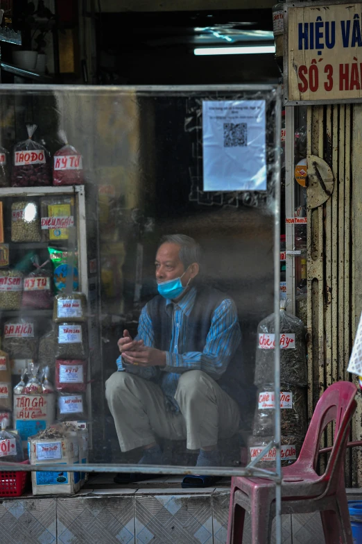 a man in a mask sits in a shop with a bag