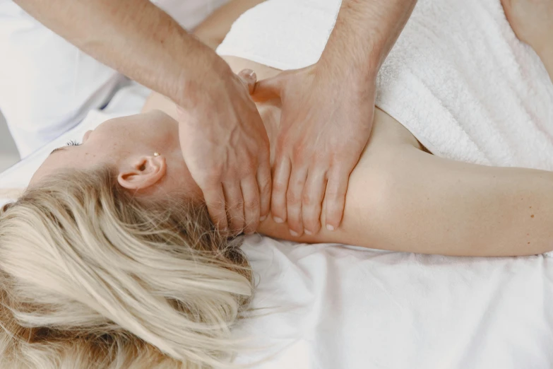 a woman laying on a white bed with her hand on the back of her body