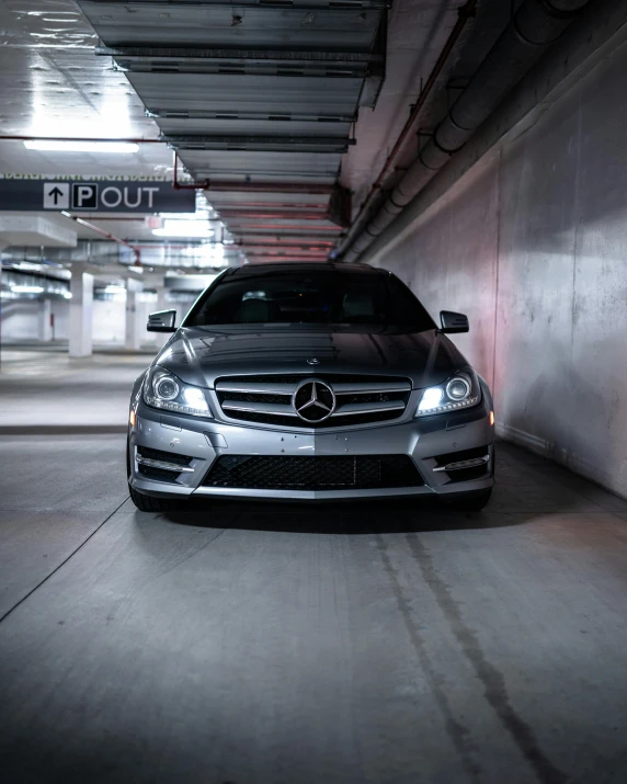 the front end of a silver car in a parking garage