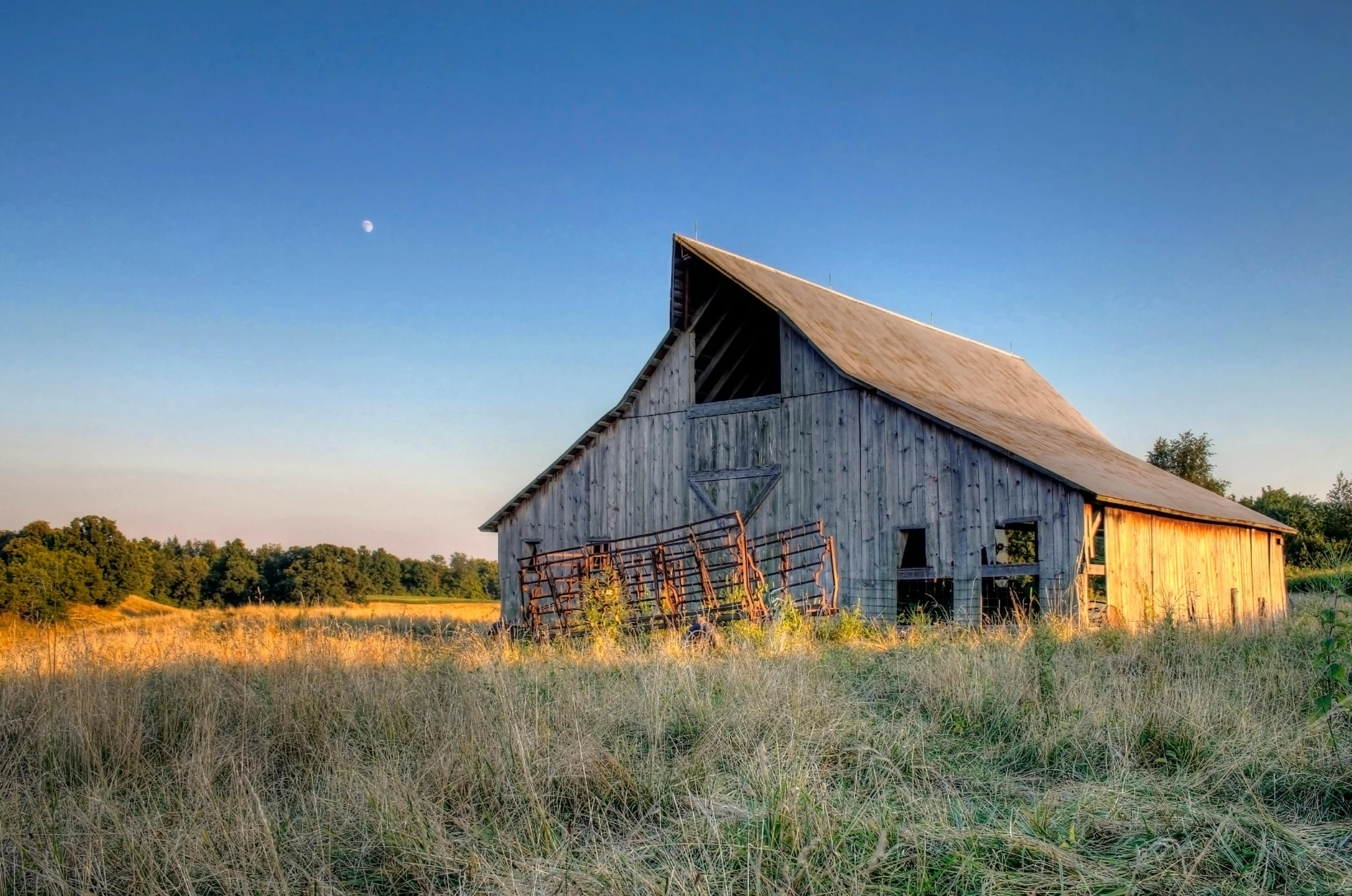 a rustic barn with a full moon behind it