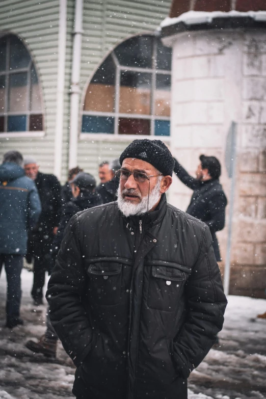 a man standing outside wearing winter clothes and wearing snowballs