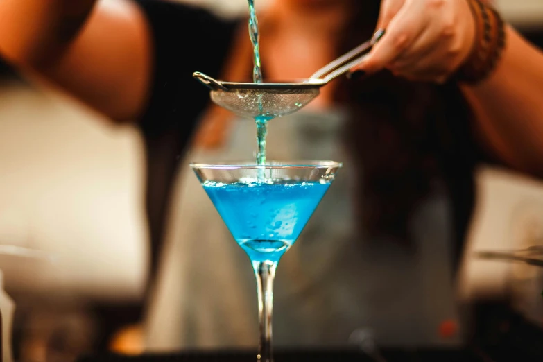 a blue drink being poured into a glass