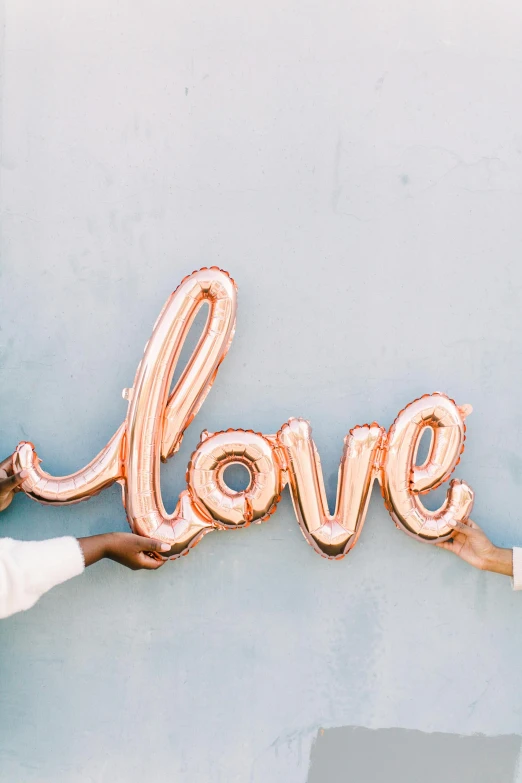 a hand holding a heart shaped balloon that says love