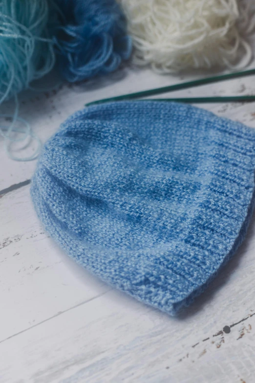 a blue hat is sitting on the floor next to a group of threads