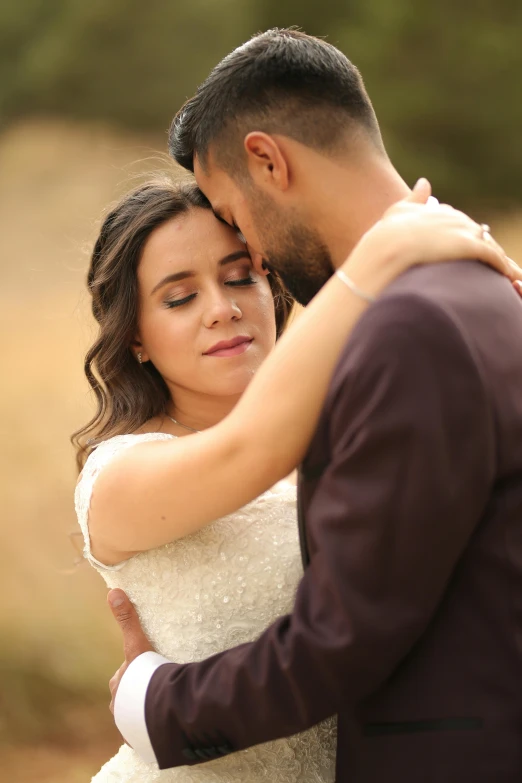 a bride and groom stand near each other in front of trees