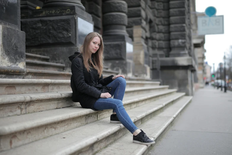 a woman sitting on the steps in an urban setting