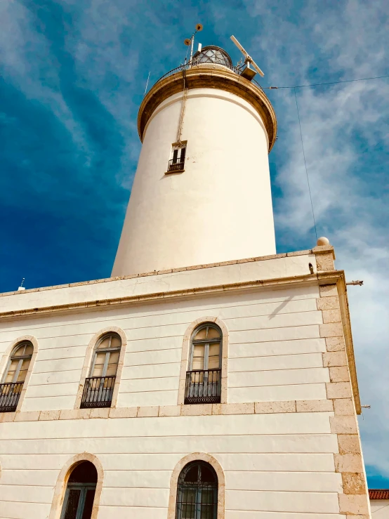 a white lighthouse with lots of windows and a tower in the background