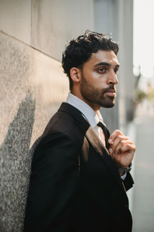 an attractive young man leaning on a wall