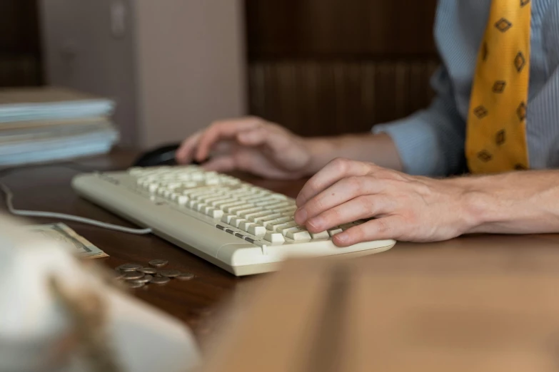 a person sitting at a desk with a computer keyboard and mouse