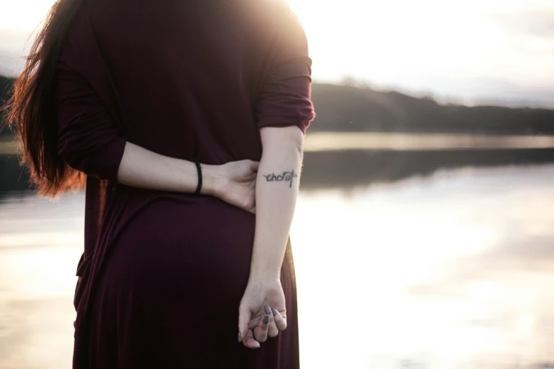 a woman standing in front of water with her hand on her hip