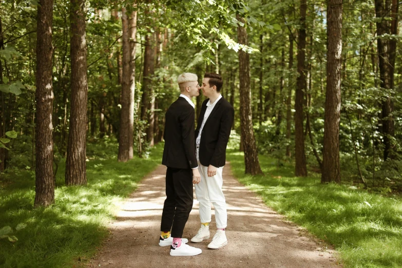 two male friends standing in the middle of a wooded trail