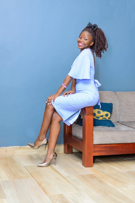 a woman sits on a couch with a blue wall