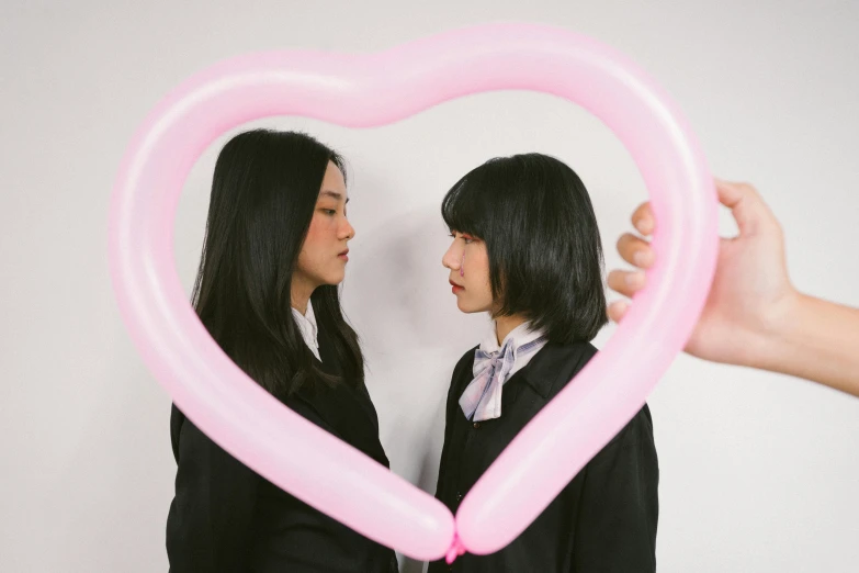 two people standing in front of a giant balloon heart