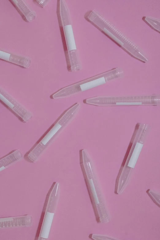 pink background with white tubes and one piece has a small toothbrush on it