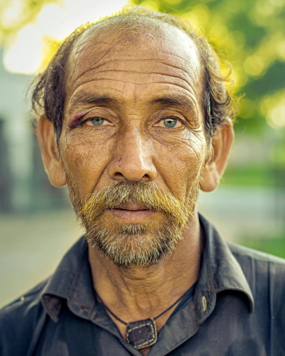 an old man with a beard and a shaved hair is staring at the camera